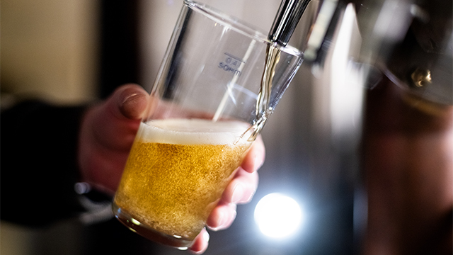 Bartender pouring crafted beer from tap in glass