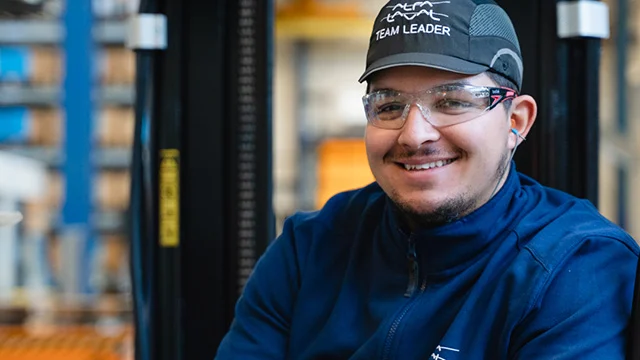Smiling man in workshop wearing team leader cap and safety glasses